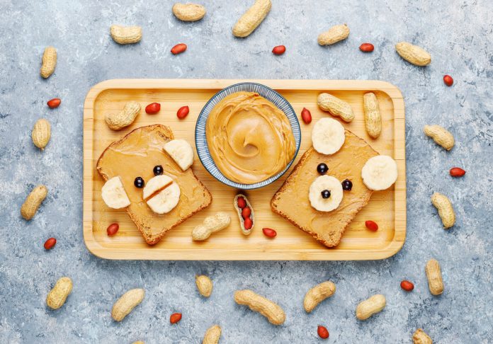 funny bear monkey face sandwich with peanut butter banana black currant peanuts top view